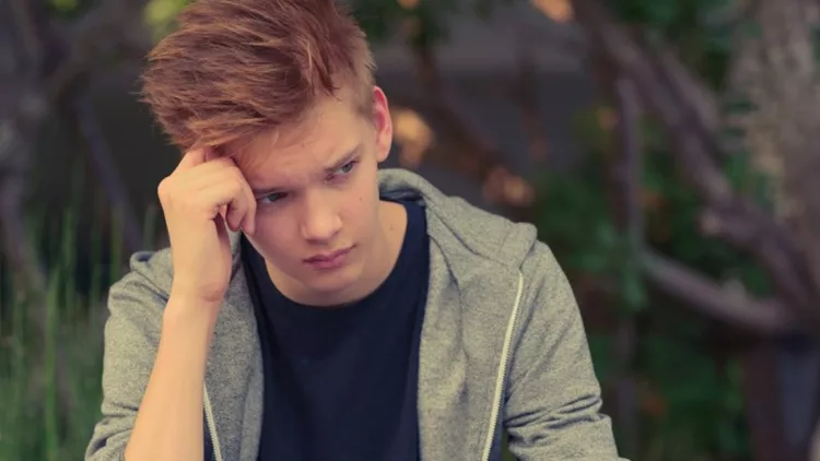 Sad teenager boy outdoors alone
