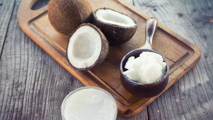 Coconut with coconut oil in jar on wooden background