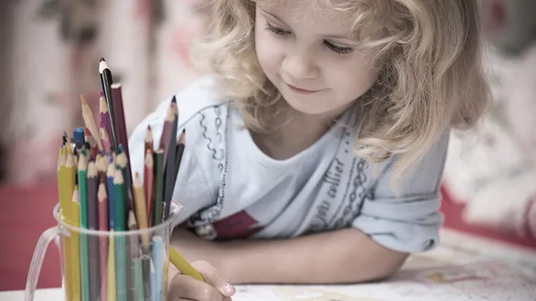Portrait of child girl drawing with colorful pencils