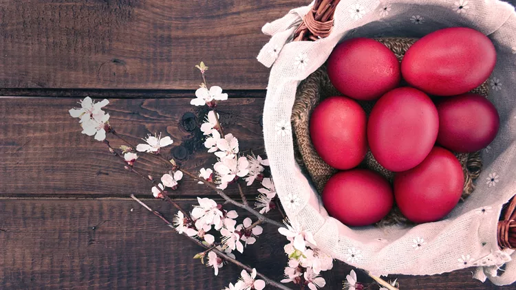 Basket with easter cake and red eggs  wooden table