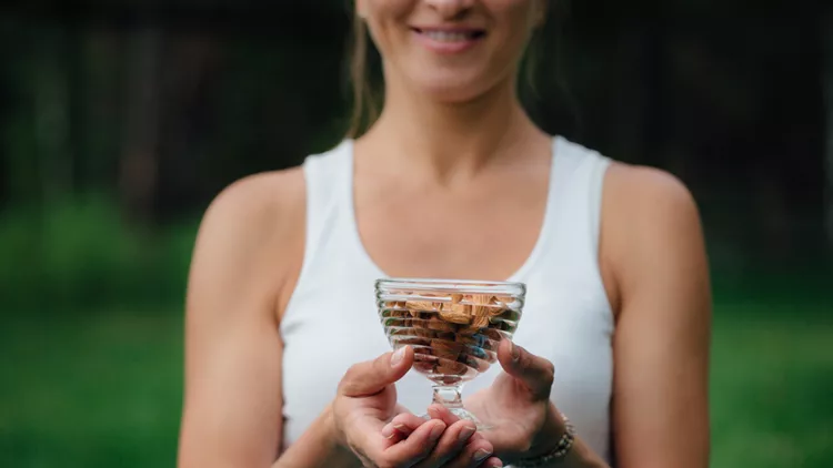 Close Up Of Woman Holding glass bowl with Almonds nuts.