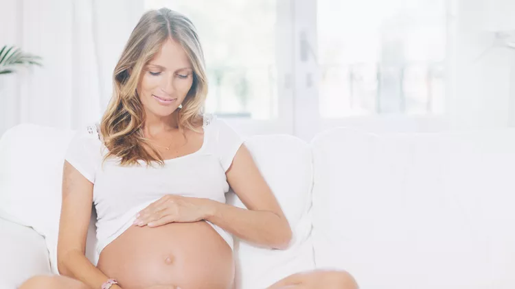 Pregnant woman relaxing on living room.