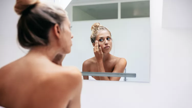 Woman applying cosmetic cream on face