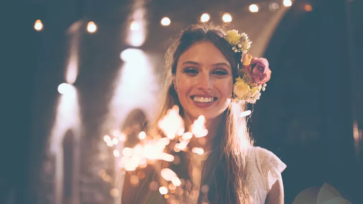 Happy bride in white wedding dress holding sparklers and celebrating