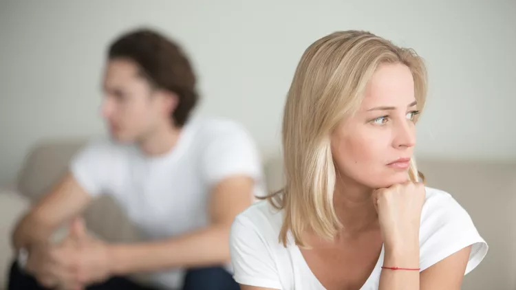 Sad woman thinking over a problem, man sitting aside