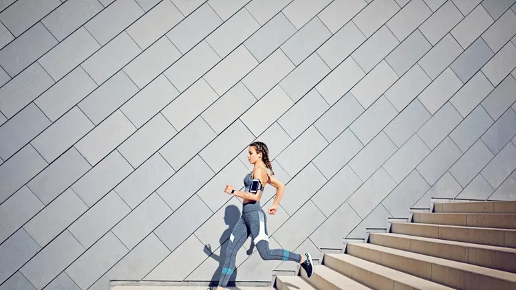 Girl is runing on the city stairs and listening the music