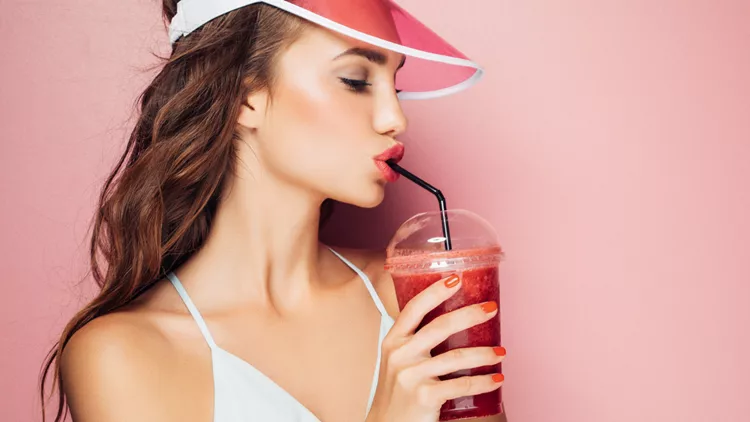 Fashion pretty cool girl drinks from cup over pink background