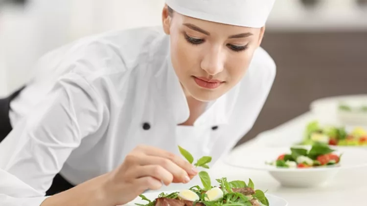 Young female chef cooking in kitchen