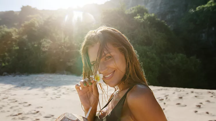 Young woman smiling with coconut on beach