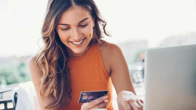 Smiling woman with credit card and laptop