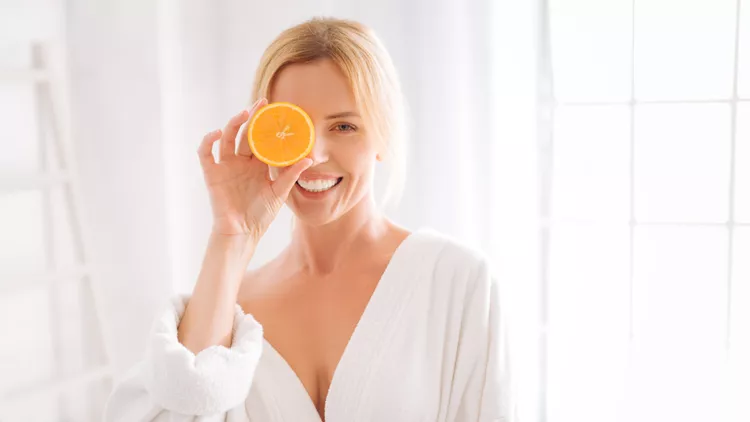 Happy woman posing with piece of orange