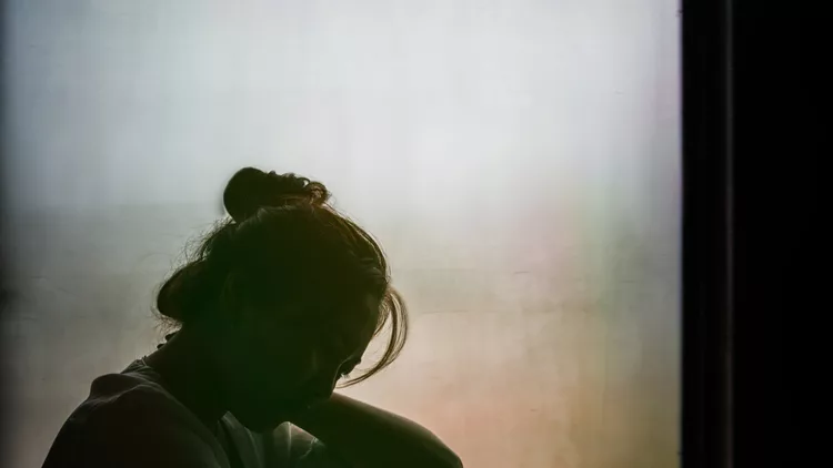 Vintage filtered on silhouette of depressed girl sitting on the window