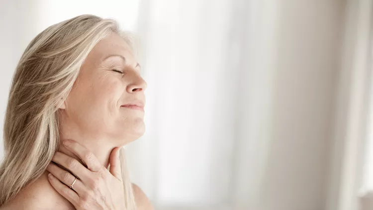 Mature woman touching neck