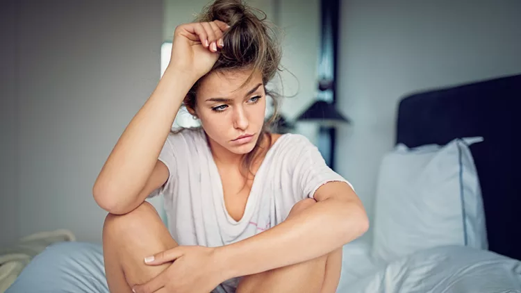 Beautiful young girl with relationship difficulties standing sad in the bed