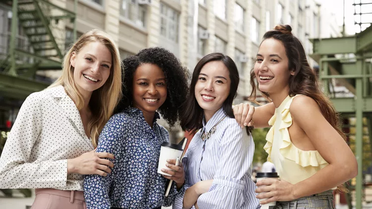 Four female coworkers smiling to camera outside