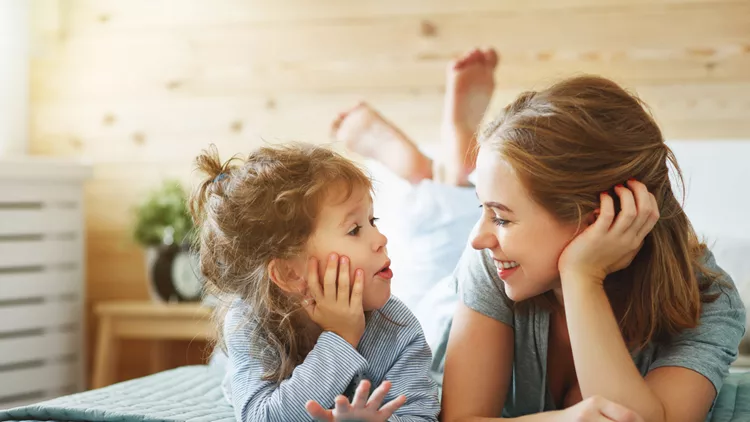 Happy family mother and child daughter laughing in bed