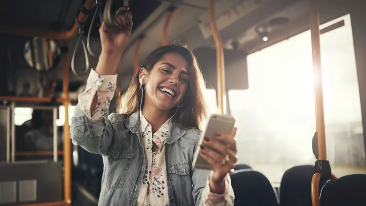 Young woman laughing while listening to music on a bus