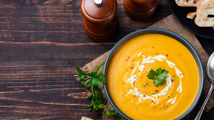 Pumpkin and carrot soup with cream and parsley Top view