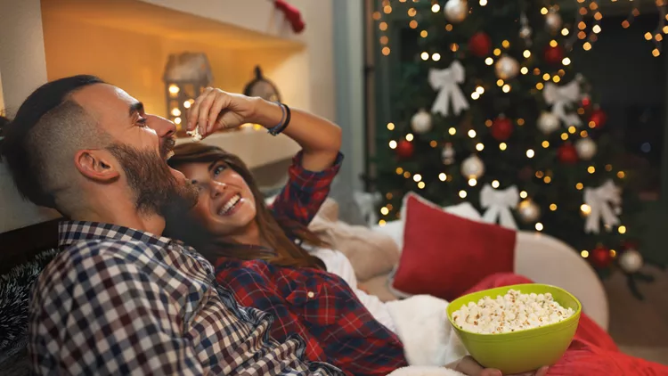 Couple at Christmas eve enjoy with popcorn while watching tv