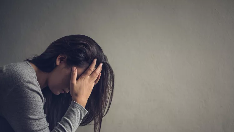 Depressed woman sitting on a chair in dark room at home. Lonly , sad, emotion concept.