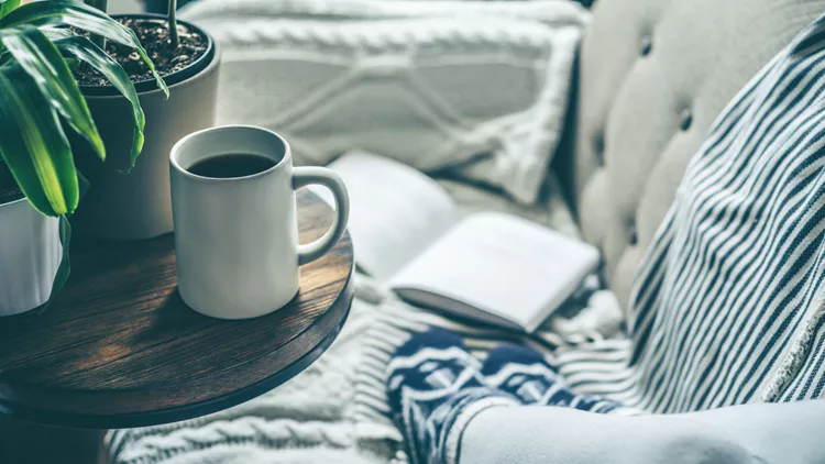 Young woman enjoying coffee and relaxing on a sofa with a book