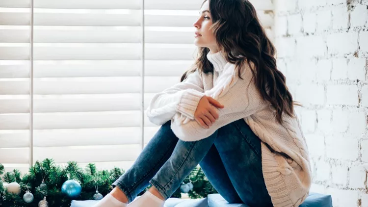 young-beautiful-woman-relaxing-on-window-sill-in-christmas-decorated-picture-id884155046