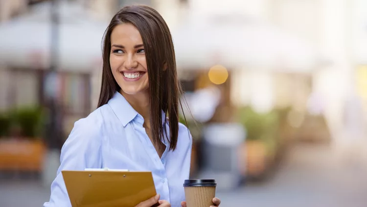 Beautiful young business woman smiling and holding documents and