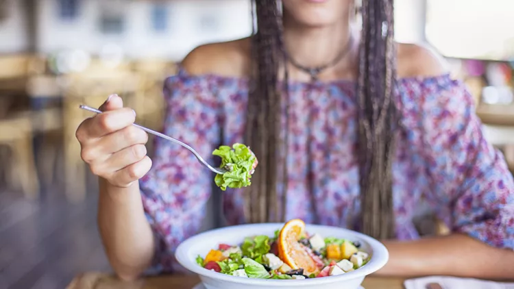 Young woman eating salad in restaurant