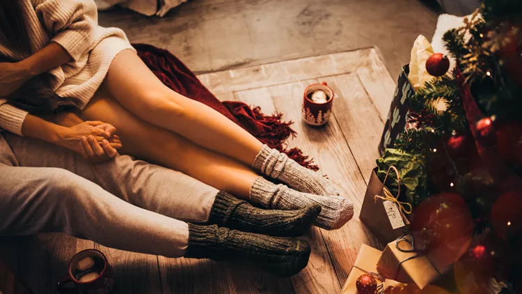 Couple holding hands and relaxing sitting under Christmas tree