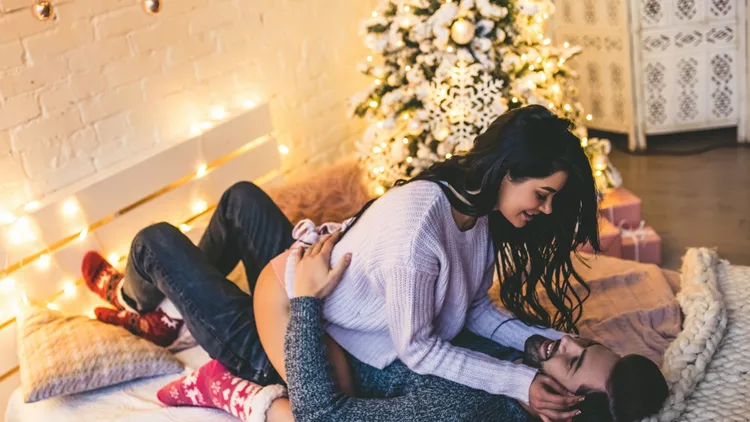 assionate romantic couple spending time before New Year near beautiful Christmas tree at home