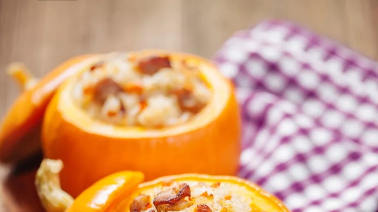 2 orange roasted &amp; stuffed pumpkins on a wooden board