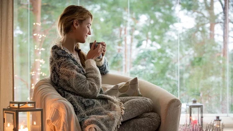 Young woman sitting home by the window