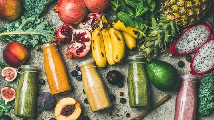 Colorful smoothies in bottles with fresh tropical fruit and superfoods