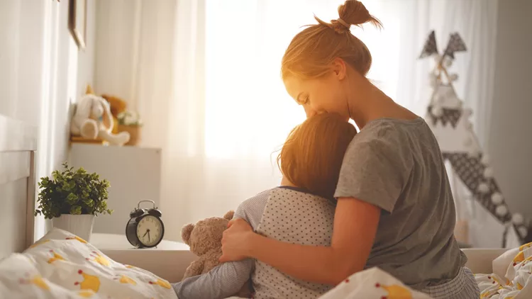 mother wakes her daughter in bed in  morning