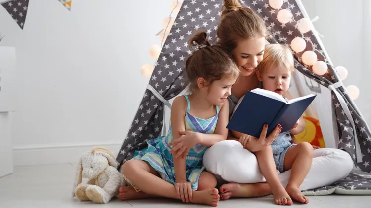 family-mother-reading-to-children-book-in-tent-at-home-picture-id924593324