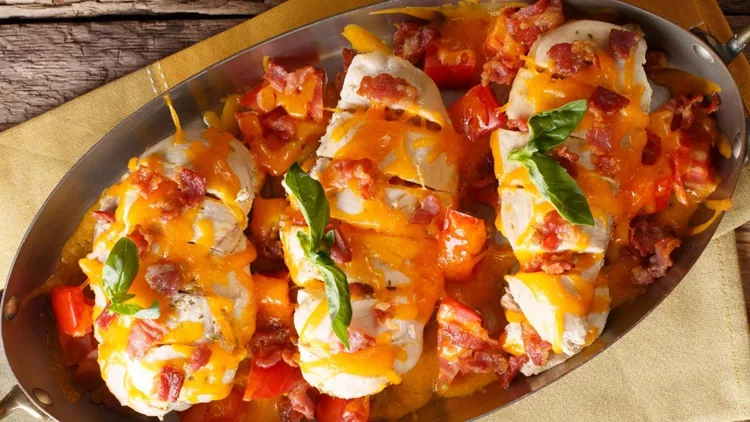 spicy-chicken-fillet-baked-with-bacon-tomatoes-and-cheddar-cheese-in-picture-id1060533260