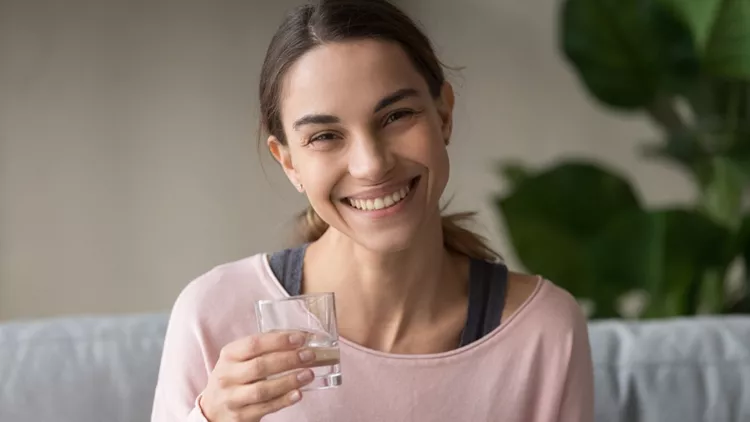 Headshot healthy woman sit on couch holding glass of water