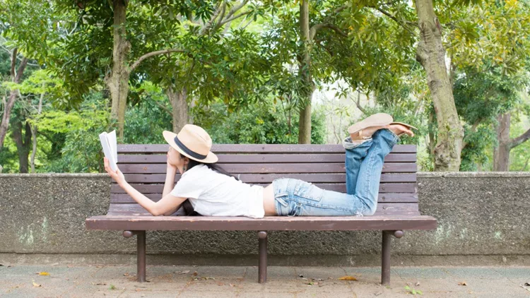 woman-reading-a-book-on-the-bench-picture-id936196488