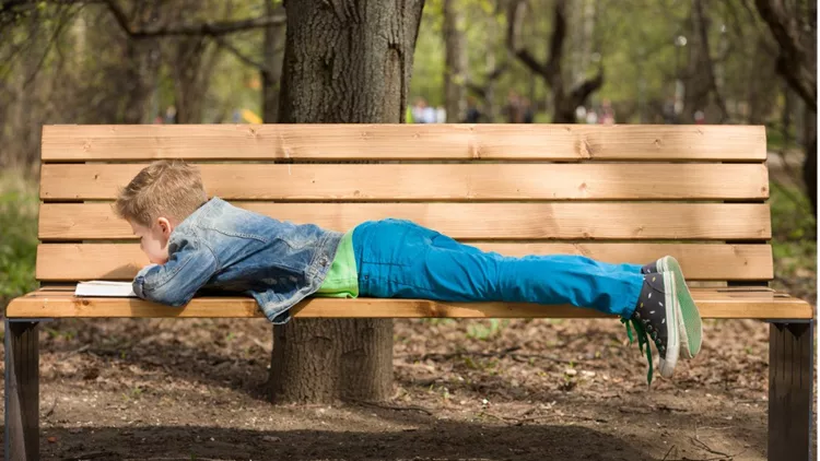 cute-kid-boy-lying-on-the-bench-in-the-park-and-reading-a-book-on-a-picture-id1139623398(1)