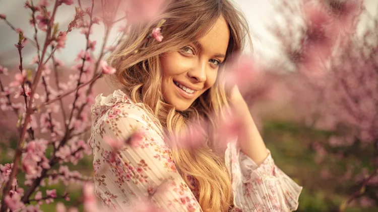 Amazing young woman posing in apricot tree orchard at spring