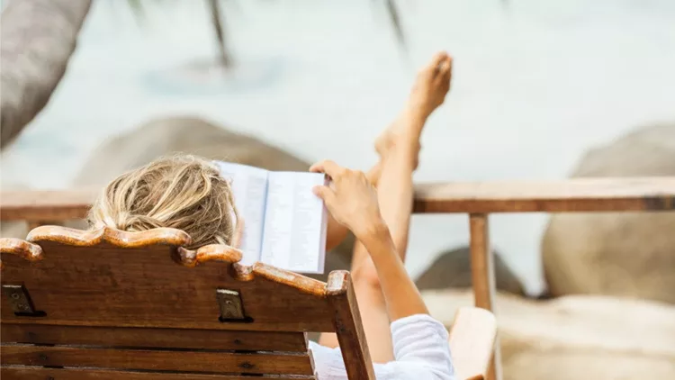 young-woman-reading-a-book-while-relaxing-on-tropical-island-picture-id519426350