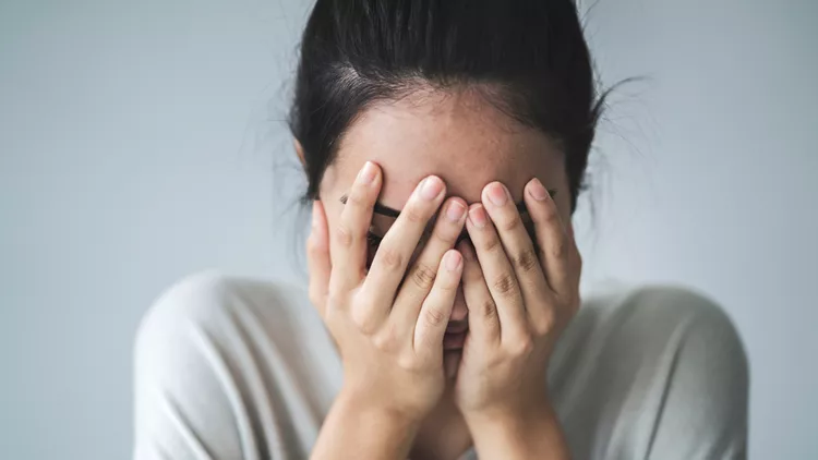 Young girl covering her face with her hands