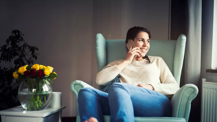 Smiling woman talking on a phone at home.