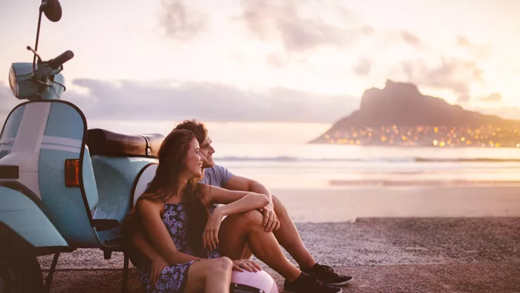 Couple at the beach with scooter looking at the sea