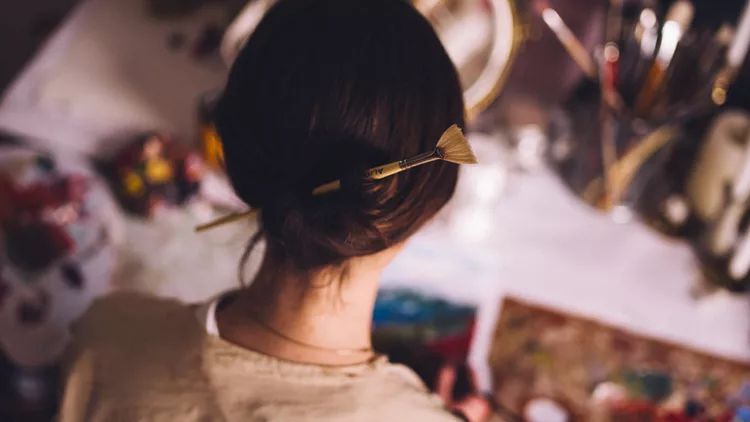 Woman artist working at her studio desk painting