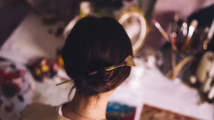 Woman artist working at her studio desk painting