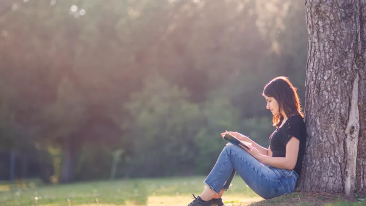 Girl reading book under a tree