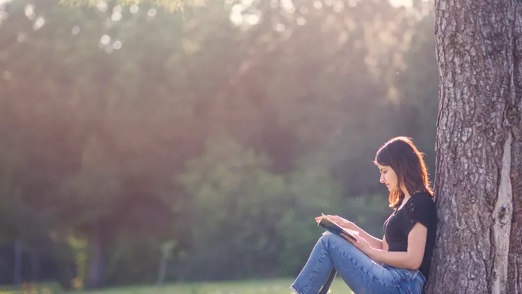 Girl reading book under a tree