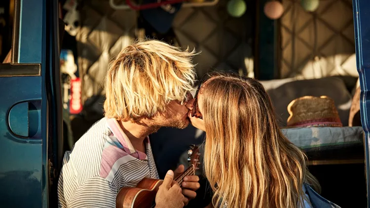 Couple kissing while sitting in doorway of van