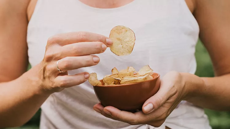 Woman eating chips snacks, close up of hands